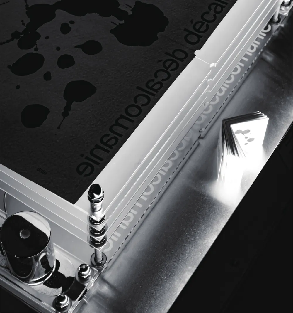 Top of an aluminium cabinet, its edge lettered décalcomanie in mirrored outline, with knurled slider knobs along the front.