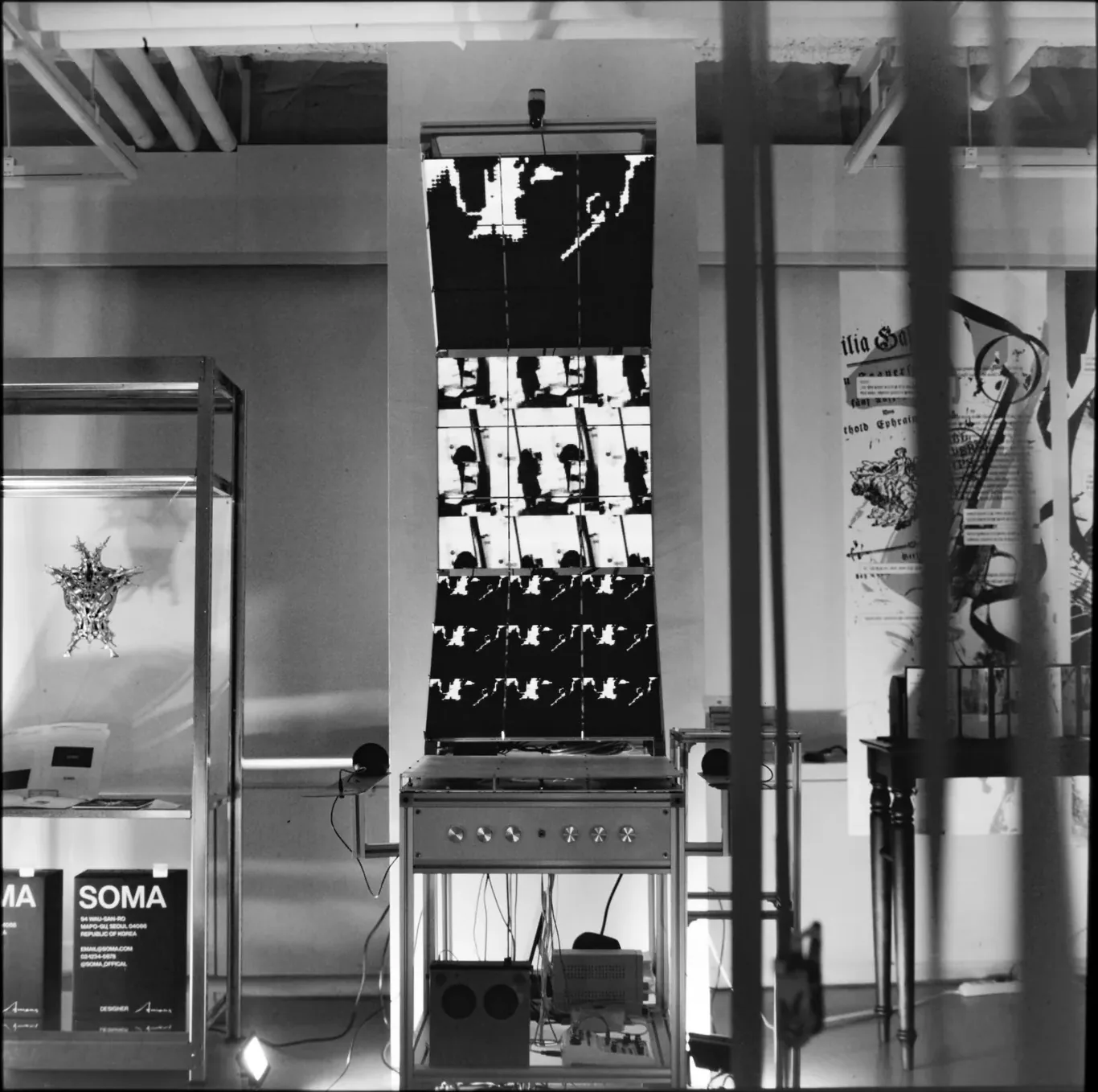 Black-and-white view of the exhibition room with the work at its centre, seen through a doorway.